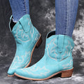 Women's blue embroidered cowboy boots with a wedge heel and pointed toe on a white background.
