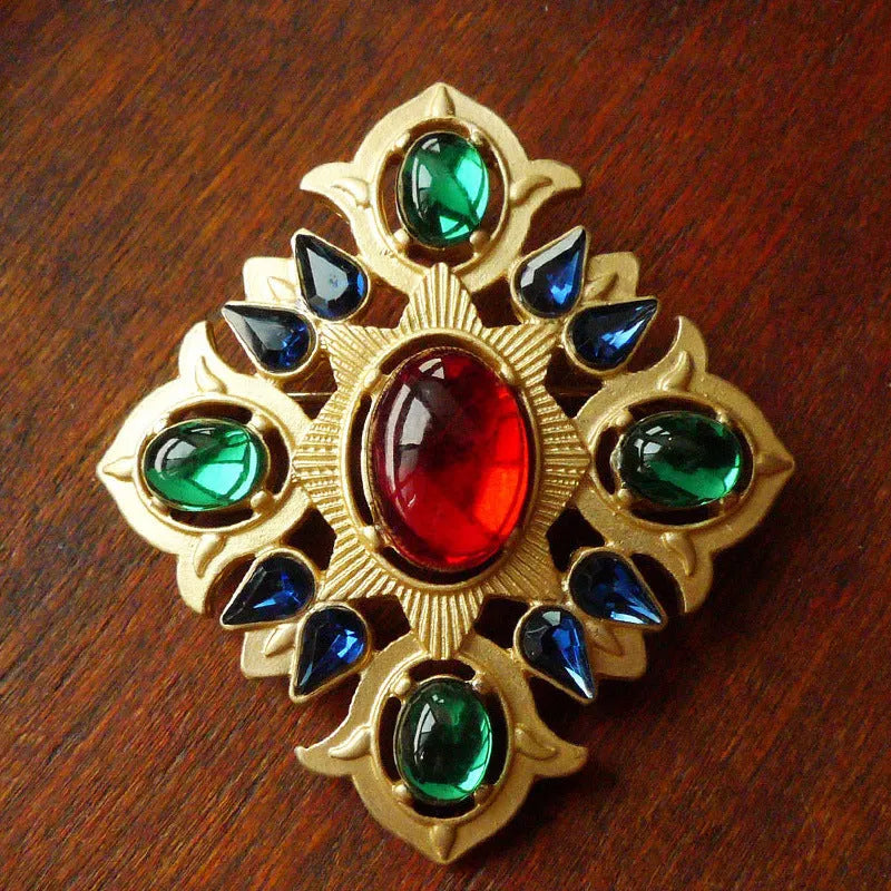 A vintage-style baroque brooch made of zinc alloy in a diamond shape on a fabric background.
