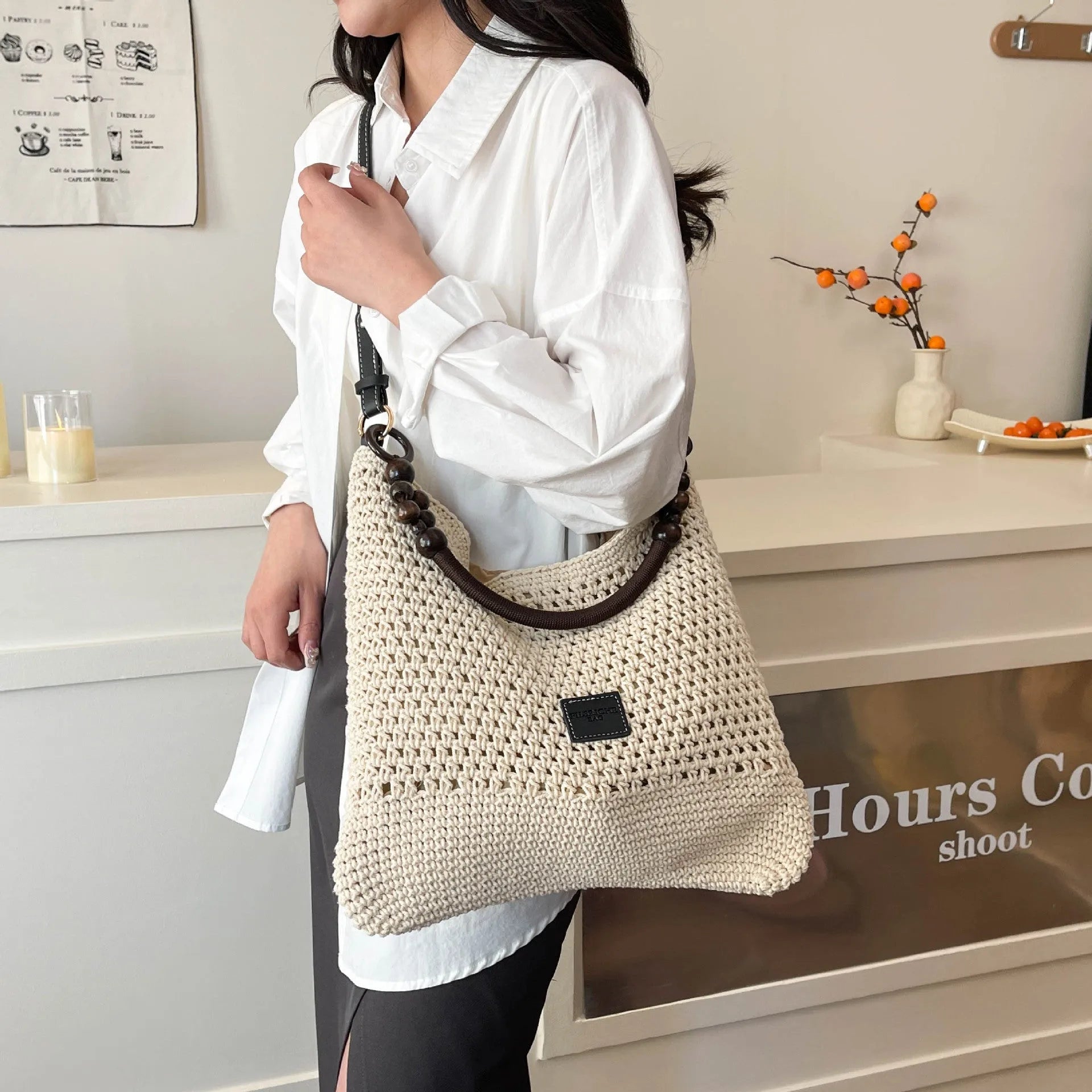 Knitted bucket-shaped tote beach bag with crossbody strap, shown in black, featuring contrasting stitching.