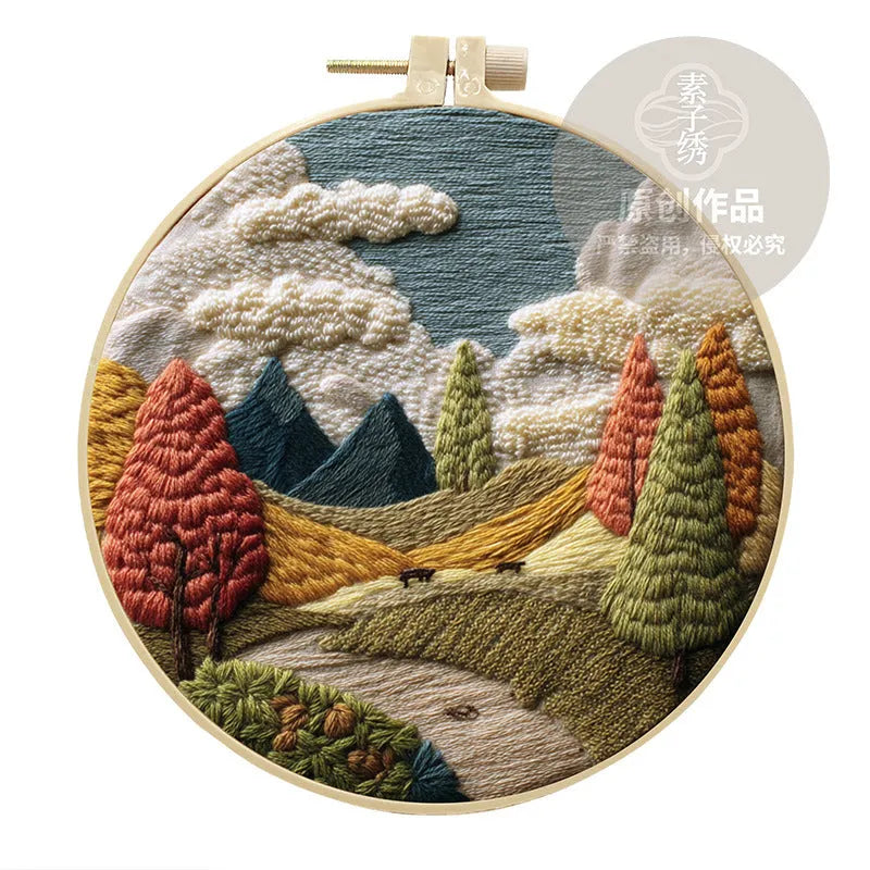 Embroidery kit with printed landscape fabric, thread, bamboo frame, and needles arranged for DIY cloth art