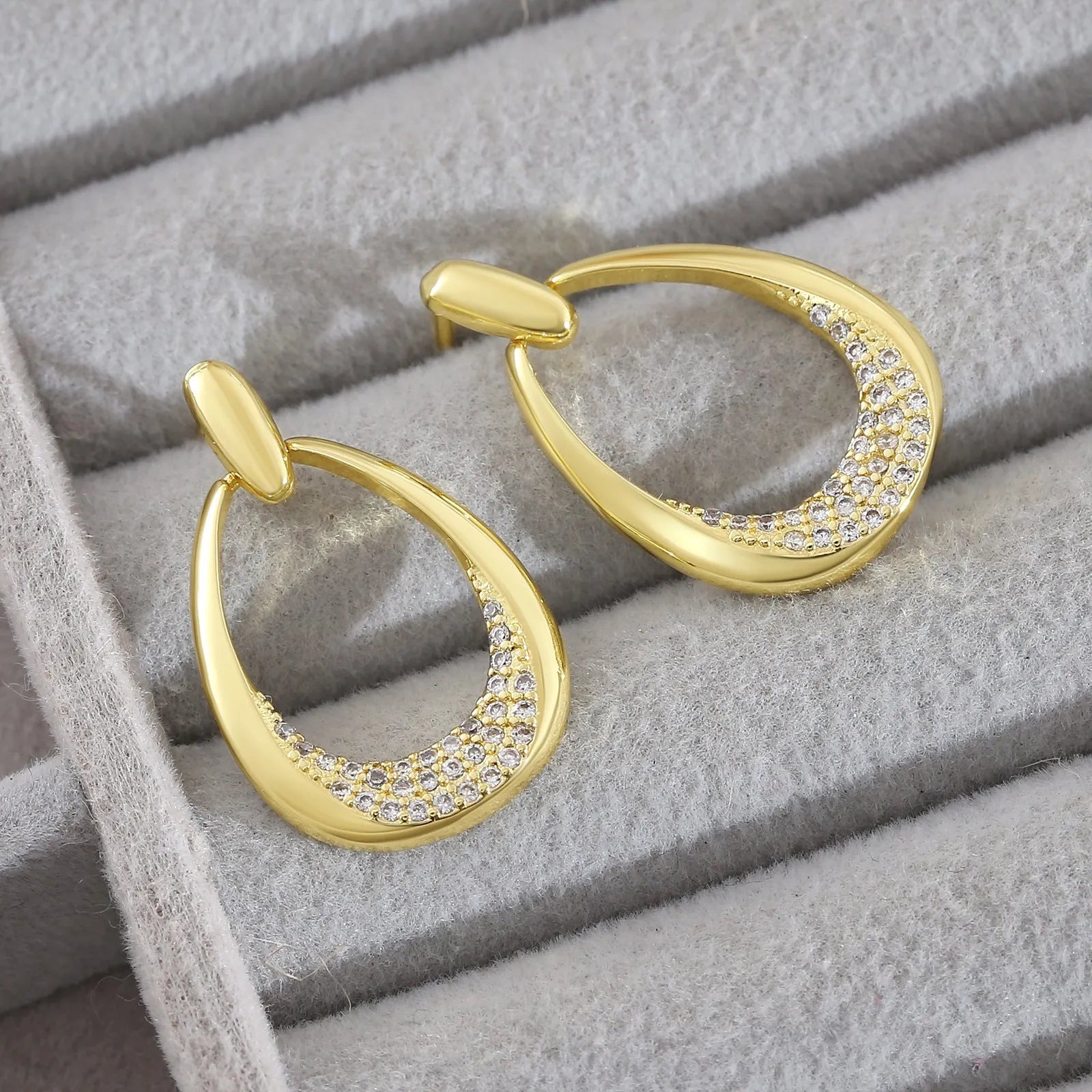 Yellow gold geometric drop earrings for women with round and oval elements, shown with handbag packaging.