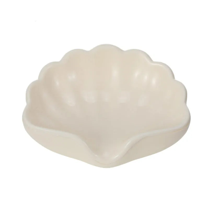 White shell-shaped plastic soap dish on a bathroom countertop.