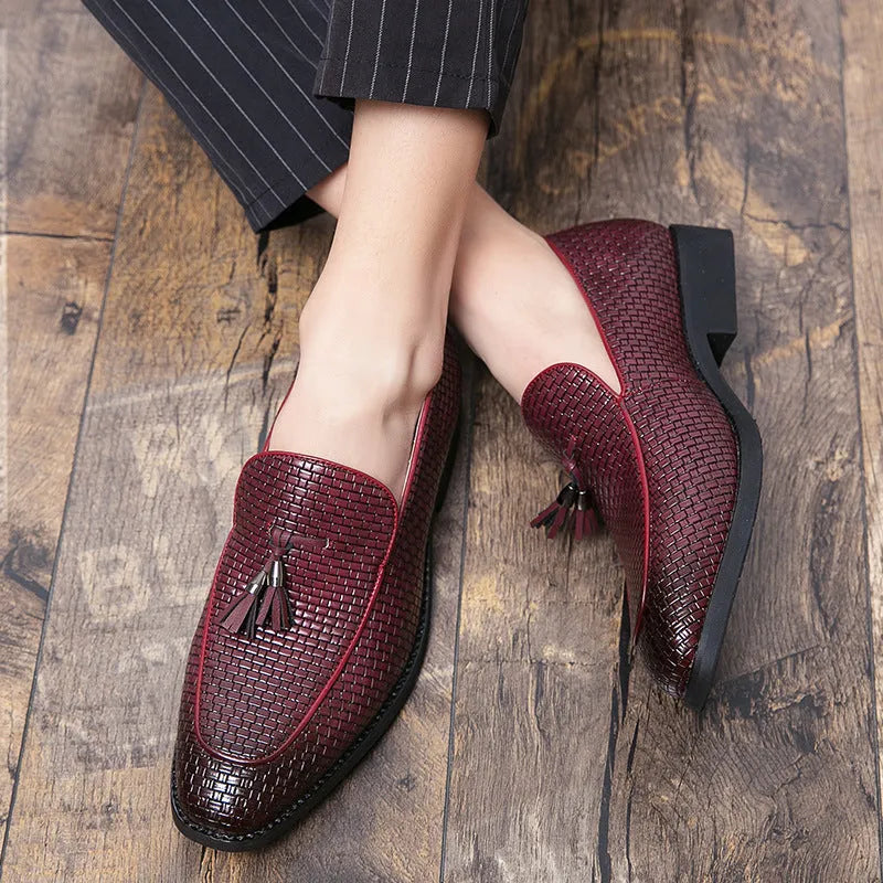 Men's black pointed toe slip on loafers with a tassel detail on the front, shown on a plain background.