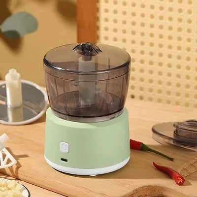 White mini electric meat grinder with transparent cup and stainless steel blade on kitchen counter