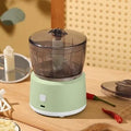 White mini electric meat grinder with transparent cup and stainless steel blade on kitchen counter