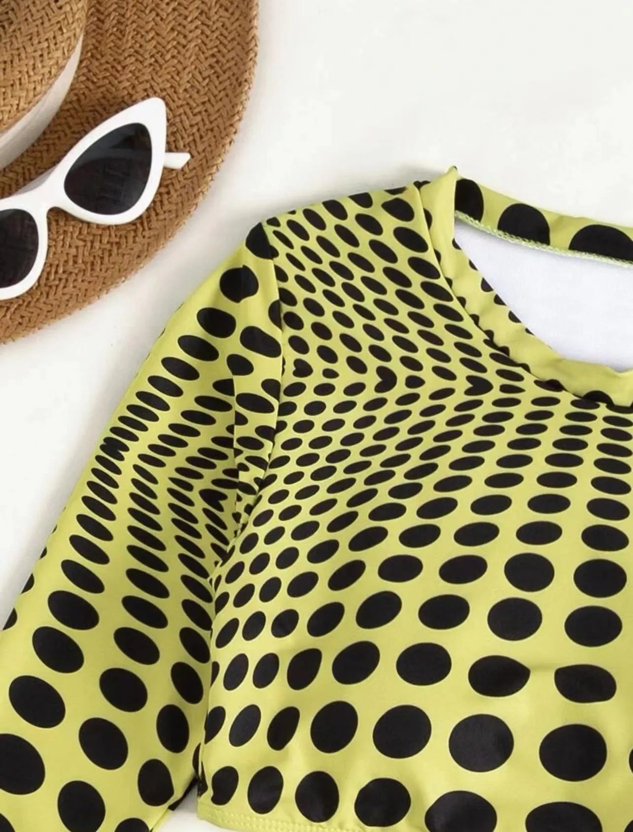 Women's green polka dot three-piece swimsuit set with bra top and skirt on hanger