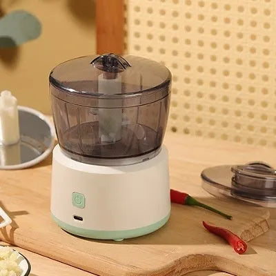 White mini electric meat grinder with transparent cup and stainless steel blade on kitchen counter