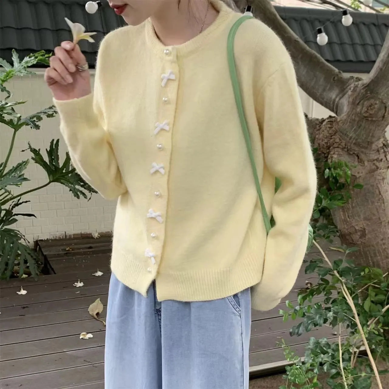 Women's solid colour cashmere cardigan with bow detail and pearl buttons on a hanger