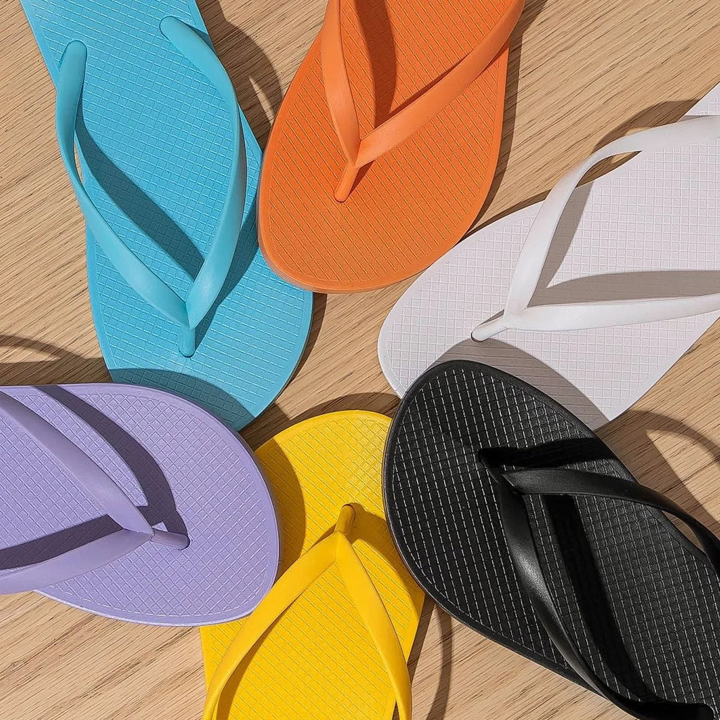 A pair of flat casual slippers with a hollow-out plastic upper and a textured non-slip PVC sole.