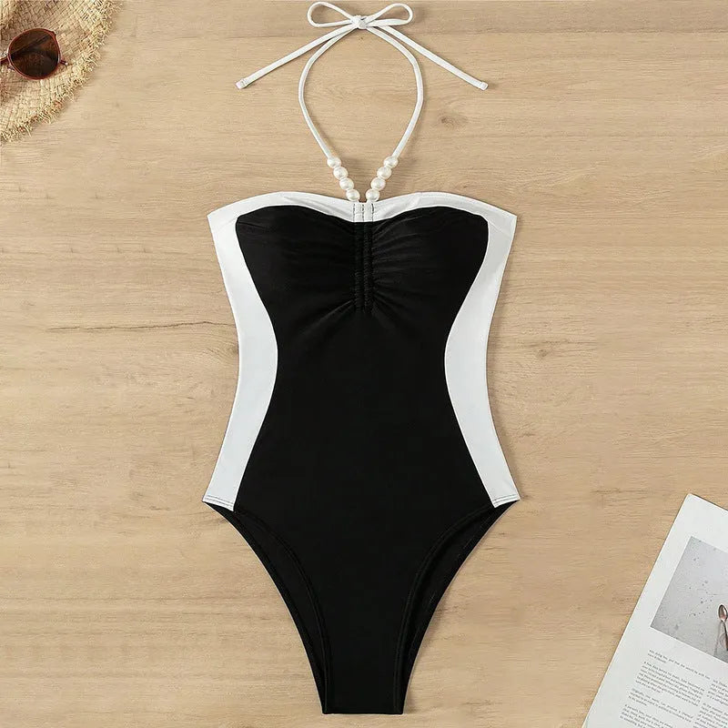 Black and white women's one-piece swimsuit with slim fit and pearl spaghetti straps on a mannequin.