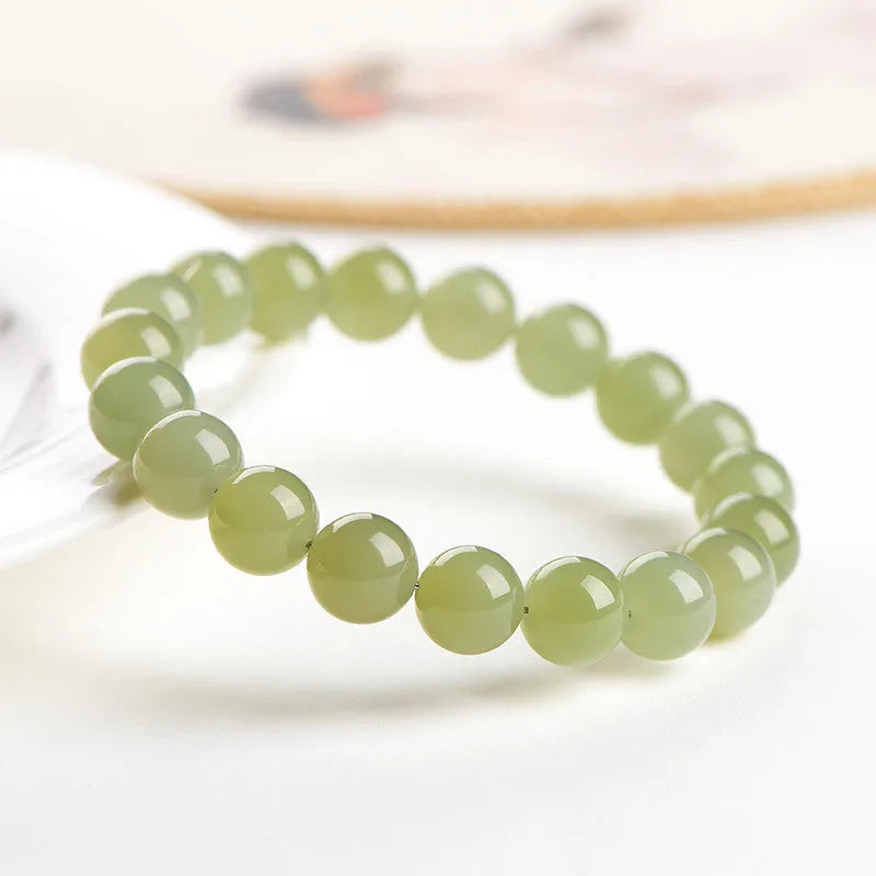Polished Hetian jade ball bead bracelet in light and deep clear water colours on a wrist.