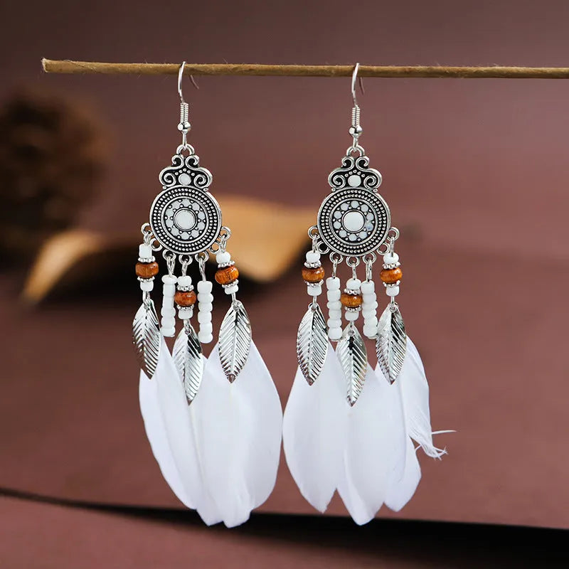 A pair of round drop leaf-shaped feather earrings in a chosen colour, showing Bohemian pattern details.