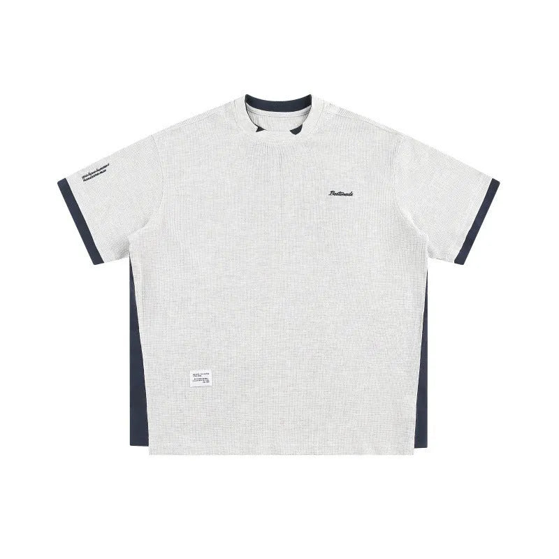 Loose grey waffle-textured t-shirt with embroidered retro lettering on the chest.