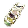 Gold winding geometric bracelet with unshaped rough natural crystal stones on a wrist.