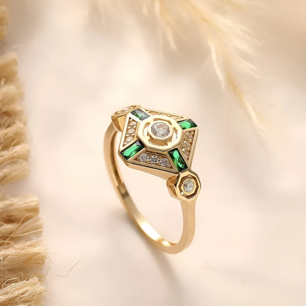 Women's square geometric fashion ring with a green emerald-coloured stone on an electroplated band.