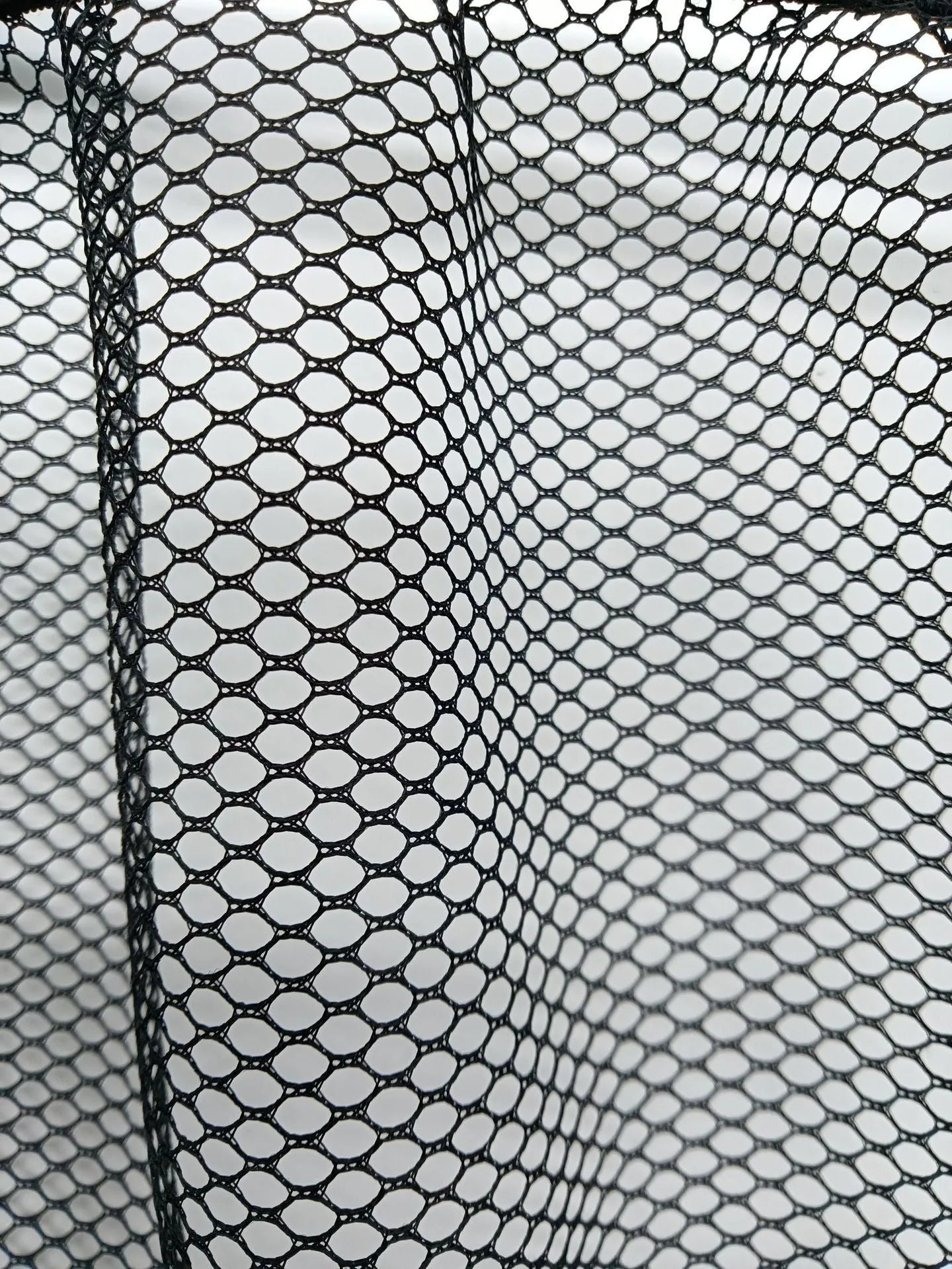 Elastic polyester storage net stretched in a car boot, holding shopping bags.