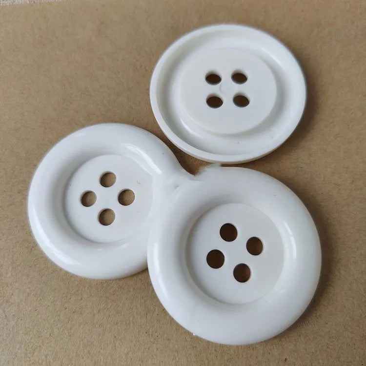 Oversized round plastic button with four holes in various colours and sizes from 38mm to 70mm.
