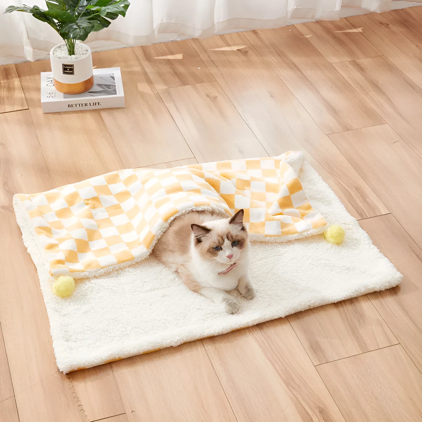 Green plaid pattern pet blanket with fur ball tassels on a sofa.