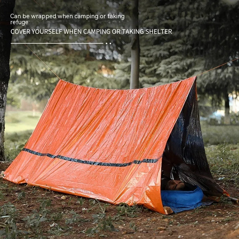 Orange portable disaster relief tent and sleeping bag kit set up outdoors.