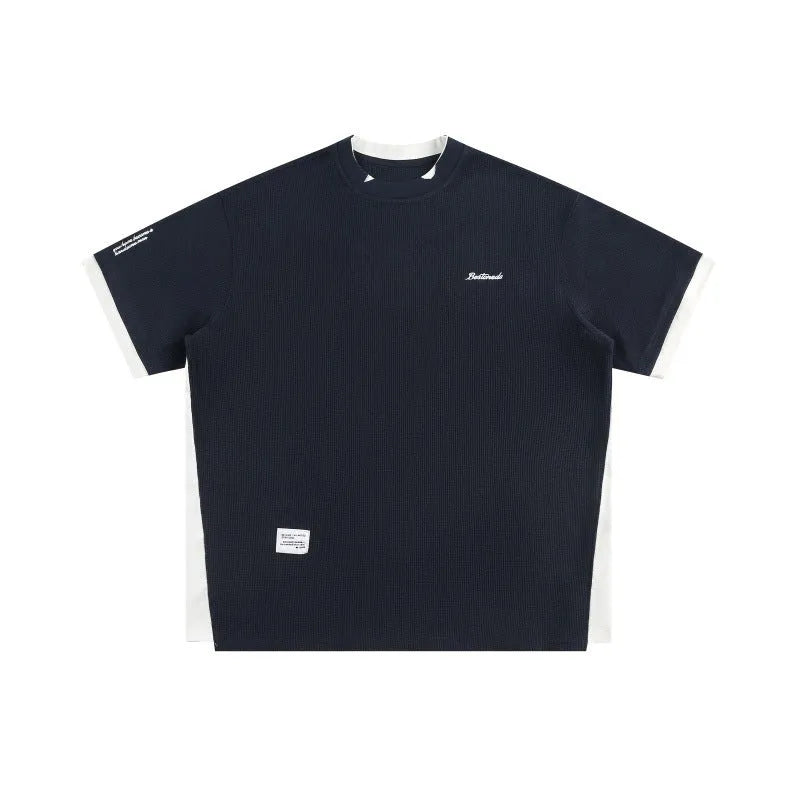 Loose grey waffle-textured t-shirt with embroidered retro lettering on the chest.