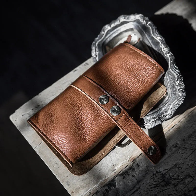 Handmade cow leather vintage wallet in black, showing tape extraction closure, 20cm long.