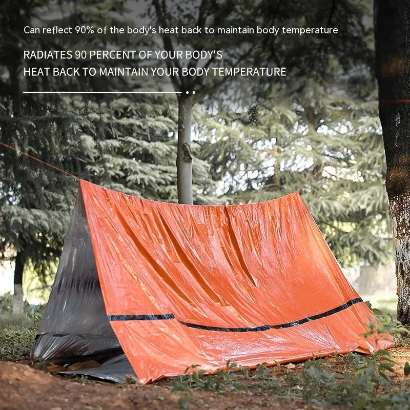 Orange portable disaster relief tent and sleeping bag kit set up outdoors.