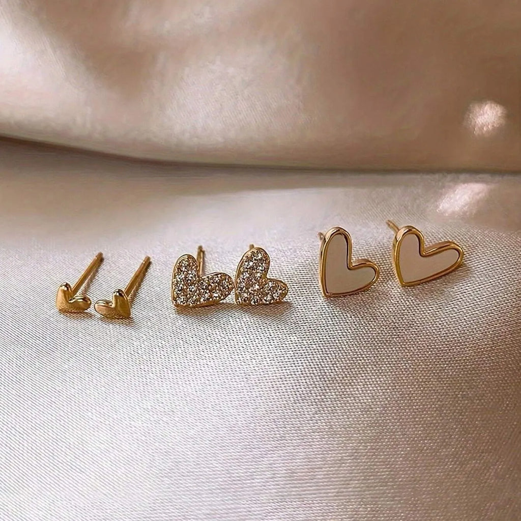 Three pairs of women's heart-shaped alloy earrings in gold, black, black-white, and pink colours
