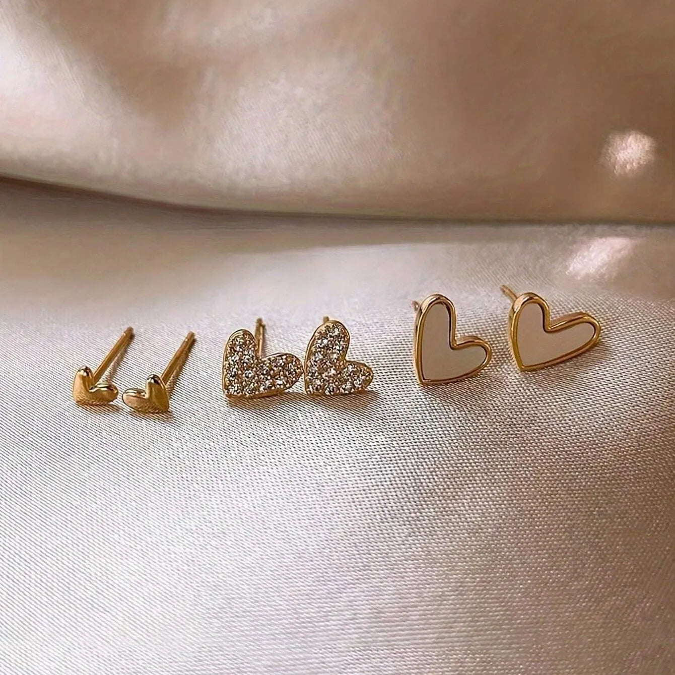 Three pairs of women's heart-shaped alloy earrings in gold, black, black-white, and pink colours