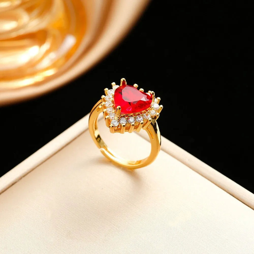 Gold red titanium steel heart jewellery set with gemstone inlay, showing necklace, earrings, and ring.