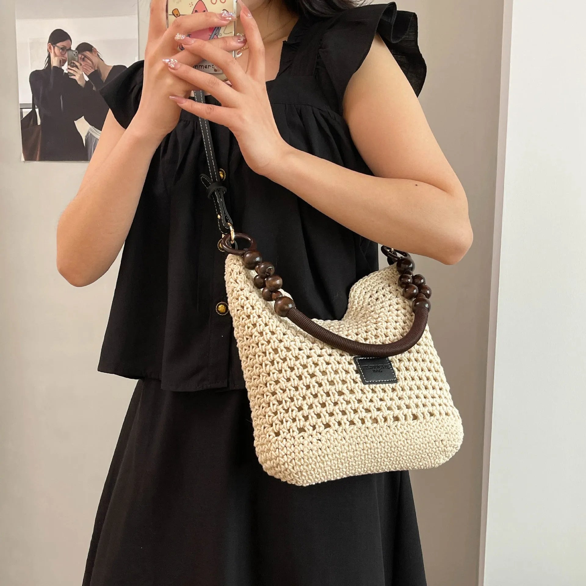 Knitted bucket-shaped tote beach bag with crossbody strap, shown in black, featuring contrasting stitching.