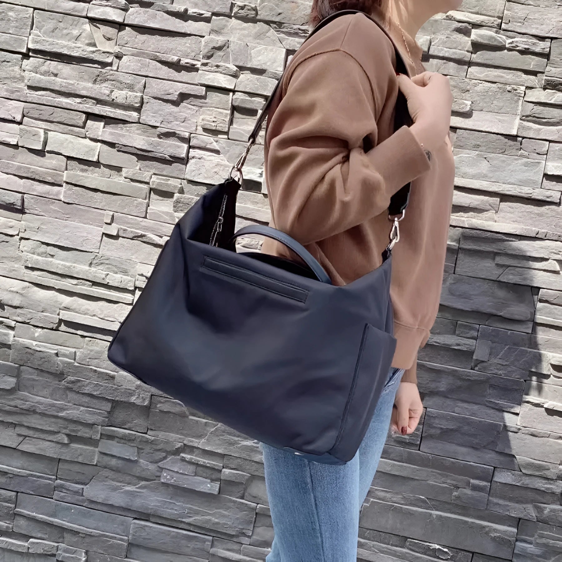 Large black nylon waterproof shoulder bag with leather trim on a model