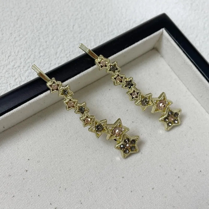 Gold electroplated alloy barrette with five-pointed star rhinestone design and broken clip construction