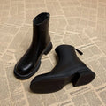 Women's black ankle boot with flat heel, round toe, and back zipper on a white background