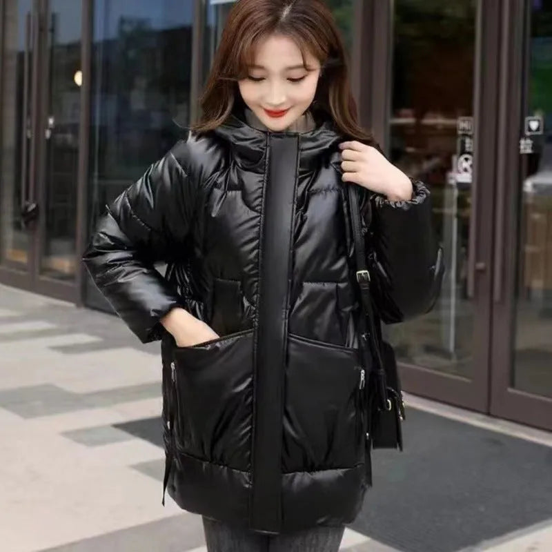 A woman wears a loose-fitting green hooded winter jacket with long sleeves.