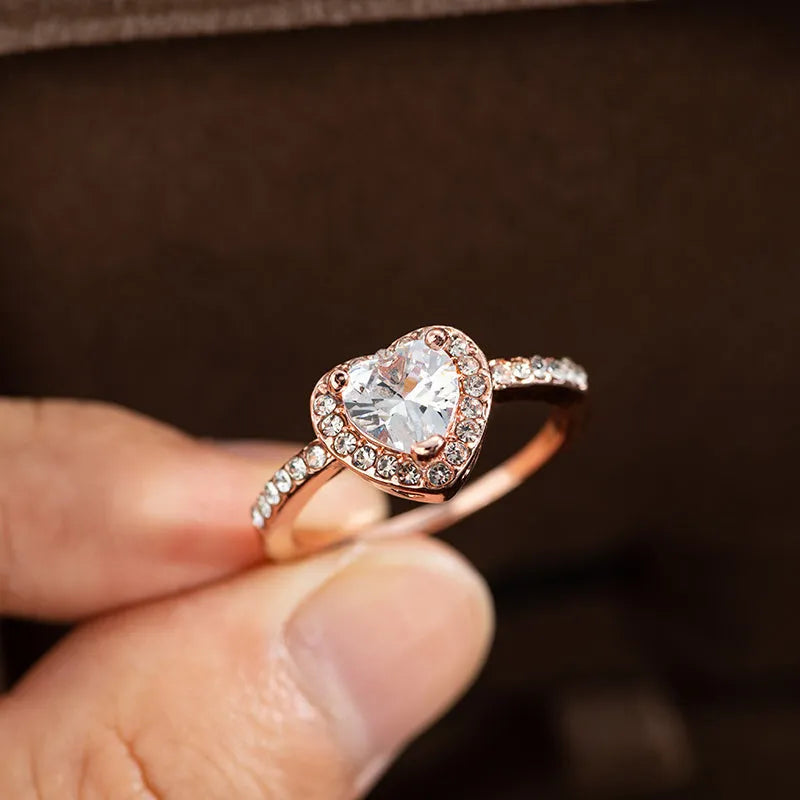 Close-up of a women's heart-shaped ring with a clear crystal centre in rose gold or silvery finish.