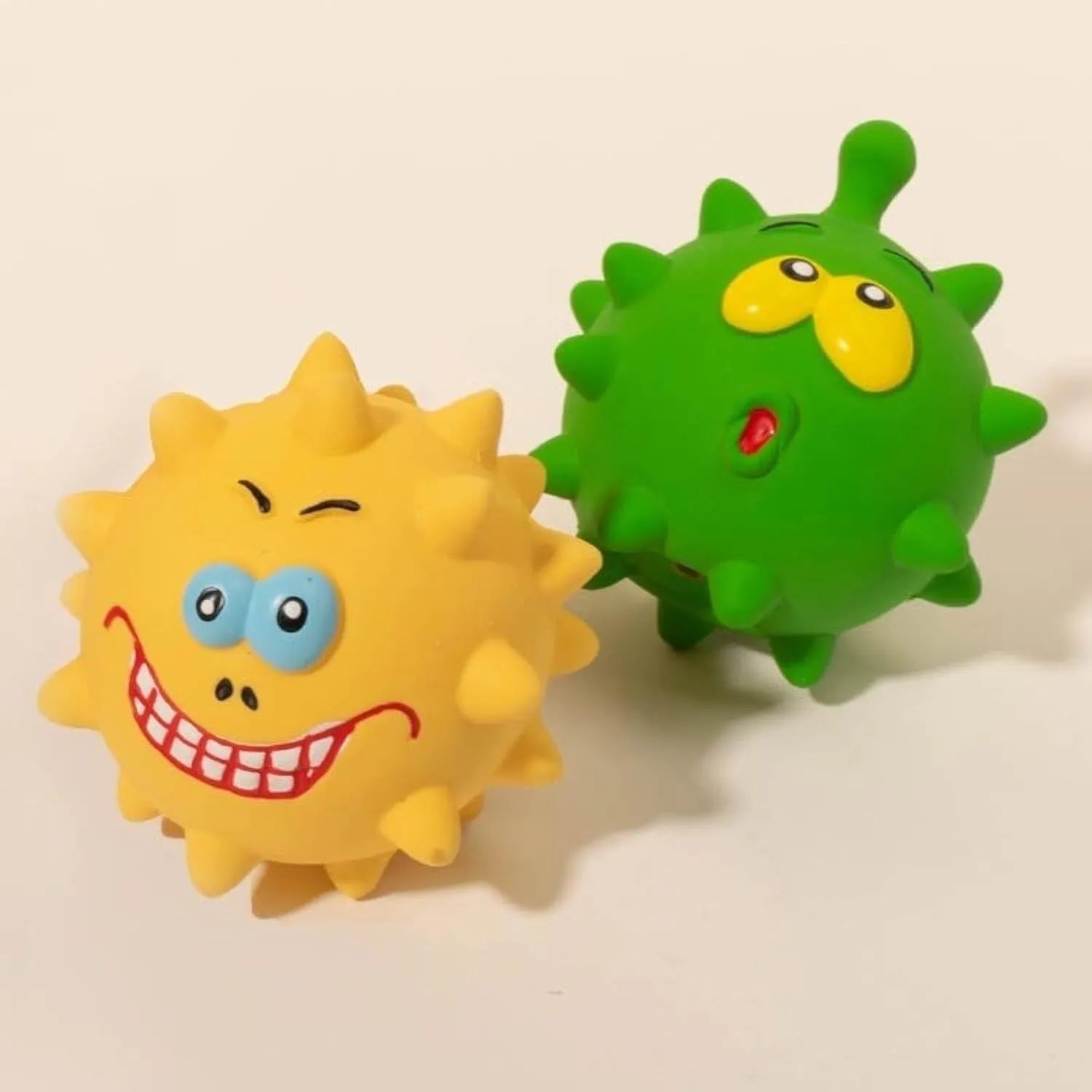 Four colourful squeaky dog balls with cute faces made from natural latex rubber with textured surfaces
