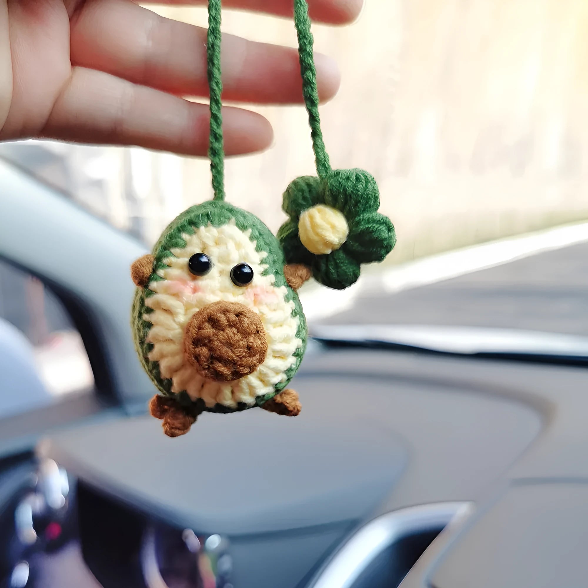 Handmade crocheted car pendant with avocado and rainbow colours hanging from rear-view mirror