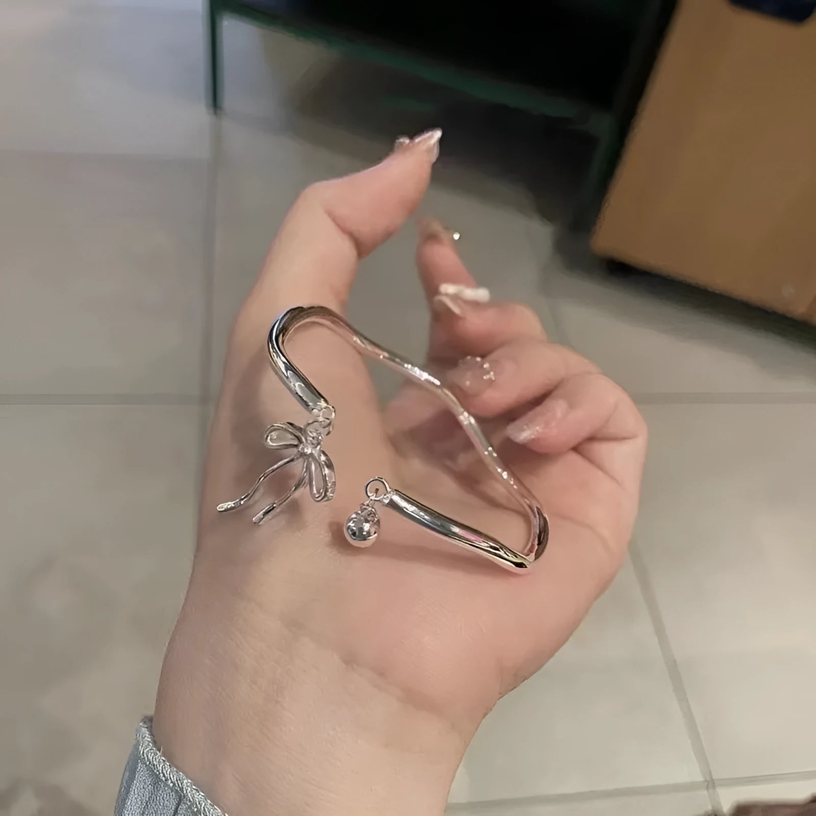 Silver adjustable bracelet with bow charm and sliding clasp mechanism