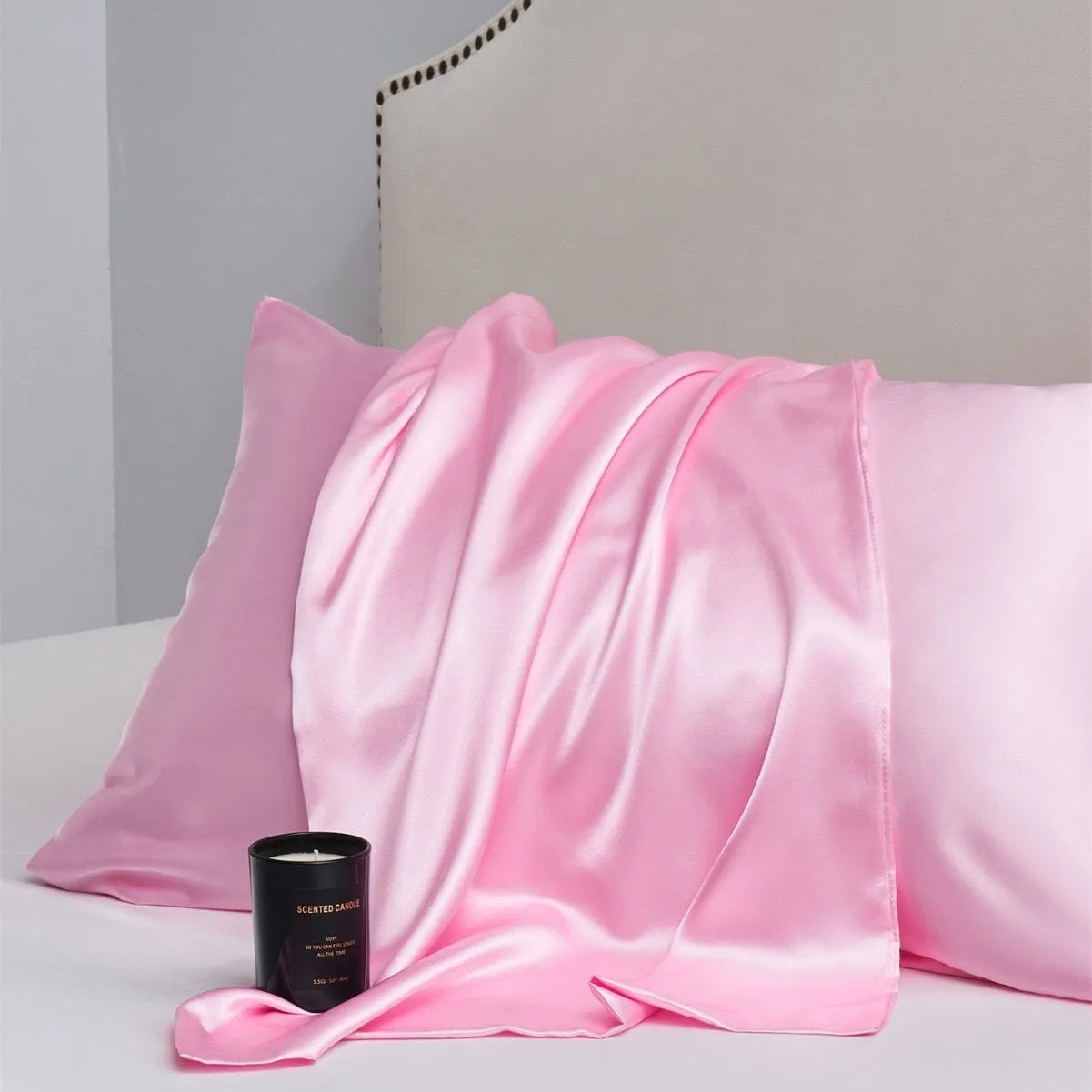 A pair of solid colour satin pillowcases in various colours and sizes on a bed.