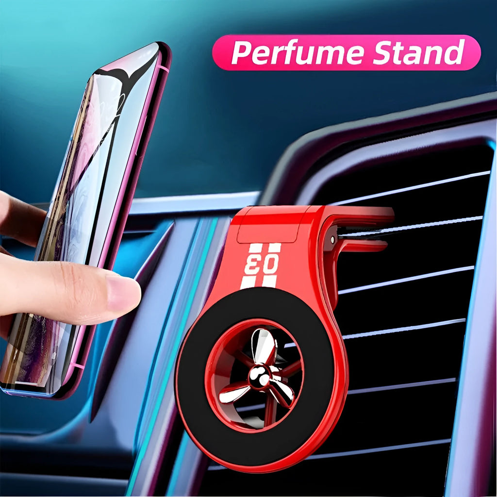 Black magnetic car phone holder clipped to a car air vent, showing a smartphone attached and the included fragrance slice.