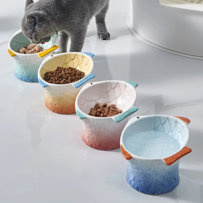 Four fish-shaped ceramic cat bowls in assorted colours with elevated design and tilted angle