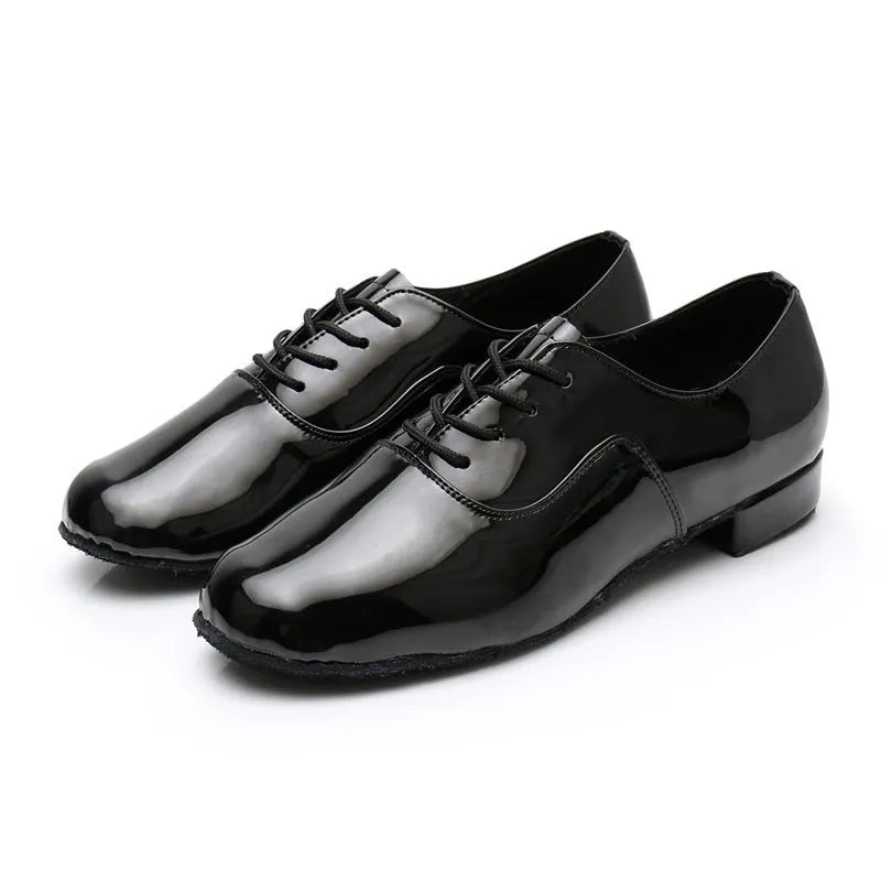 Men's black dancing shoes with a synthetic leather upper and calf leather sole, shown on a studio floor.