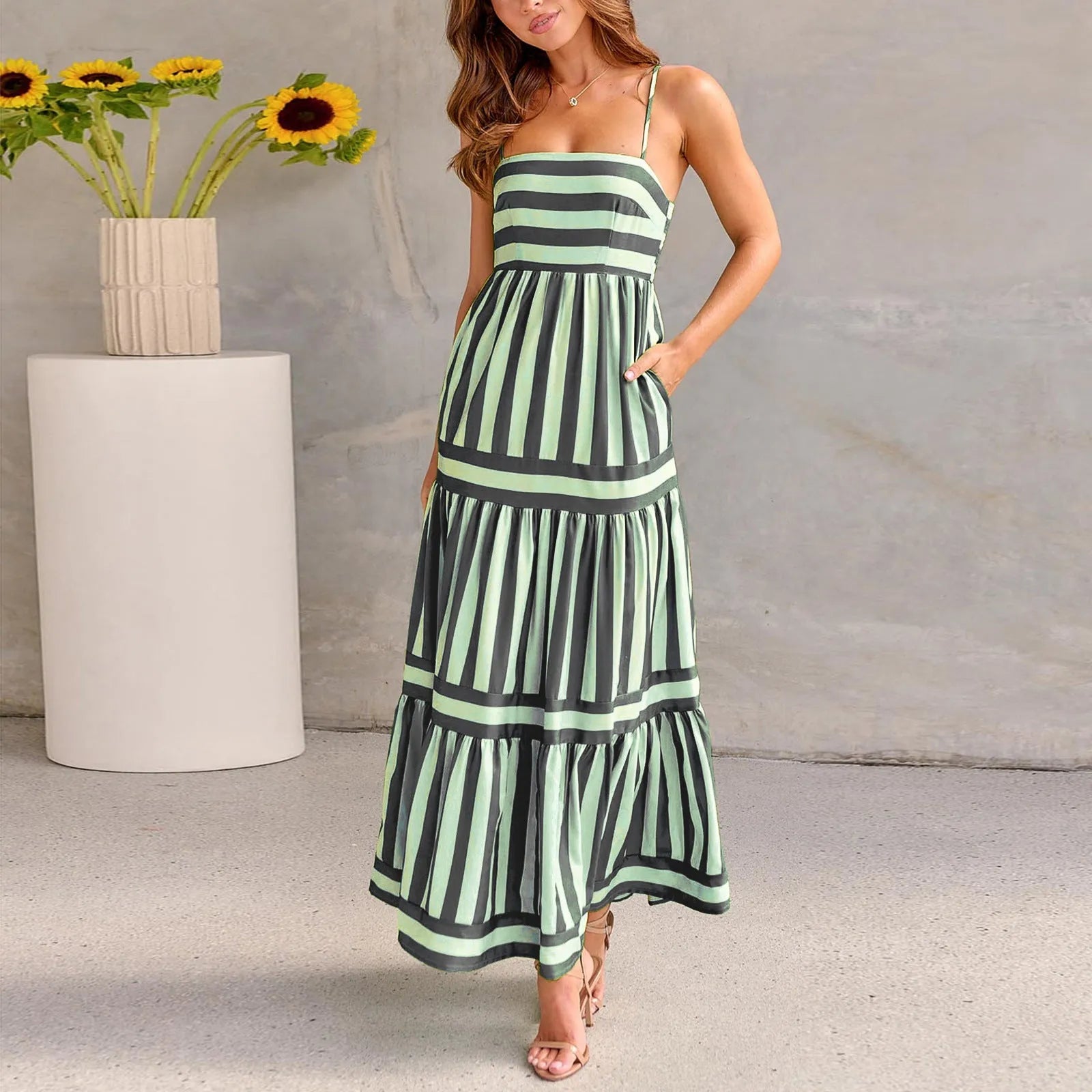 A woman wearing a striped backless suspender summer dress with a square neckline and side pockets.