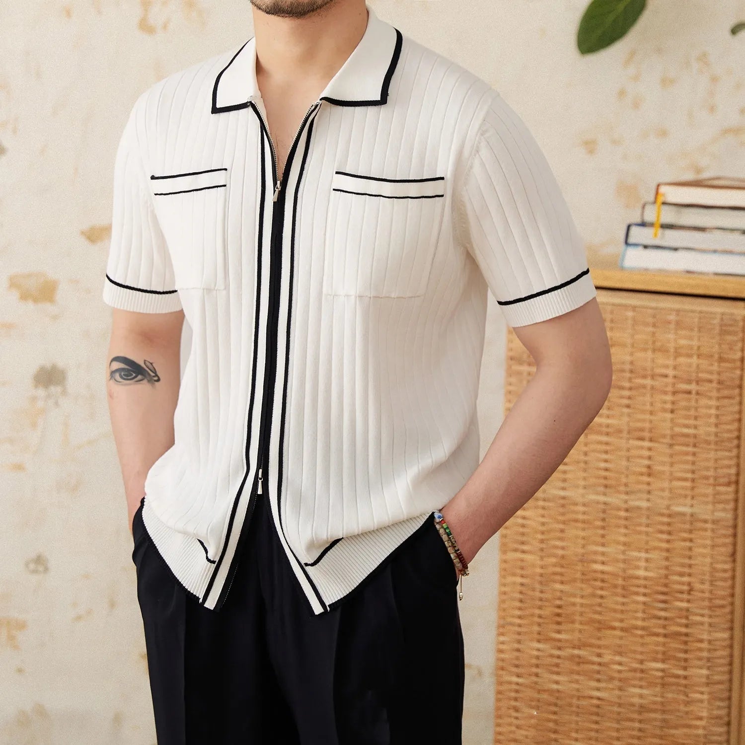 Man's slim fit black knitted polo shirt with lapel collar and short sleeves on a hanger.