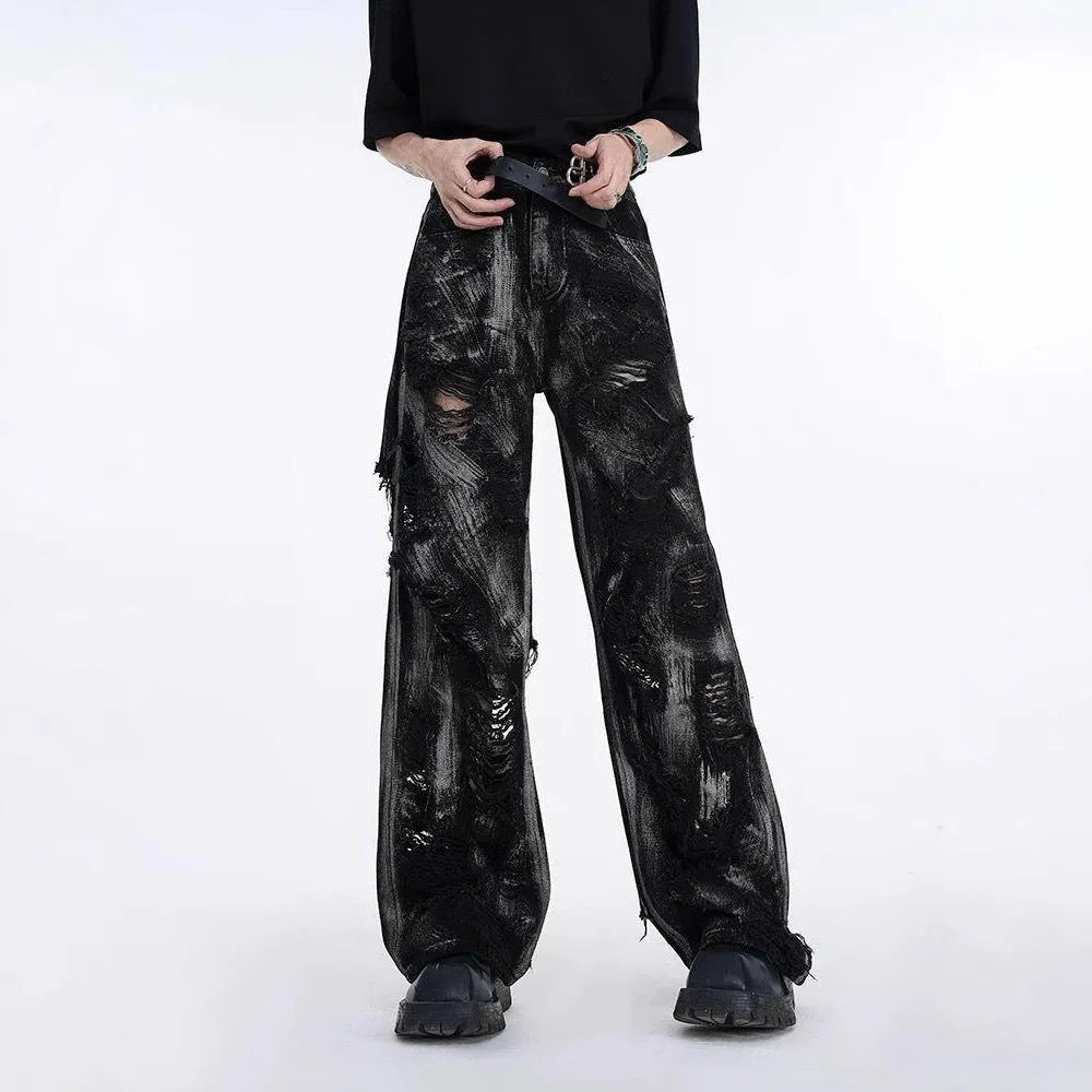 Men's black denim jeans with a heavyweight washed and graffiti-style distressed finish on the legs.