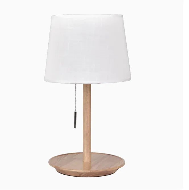Walnut-coloured solid wood bedside lamp with white fabric shade on wooden table