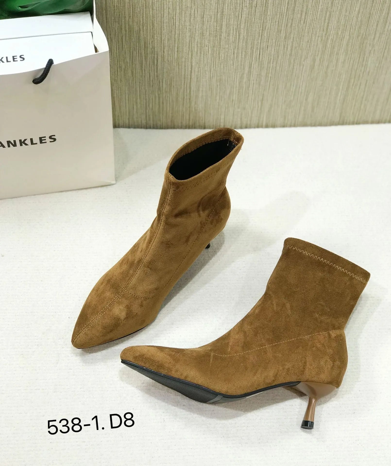 Black pointed toe ankle boots with a high stiletto heel on a woman's foot.