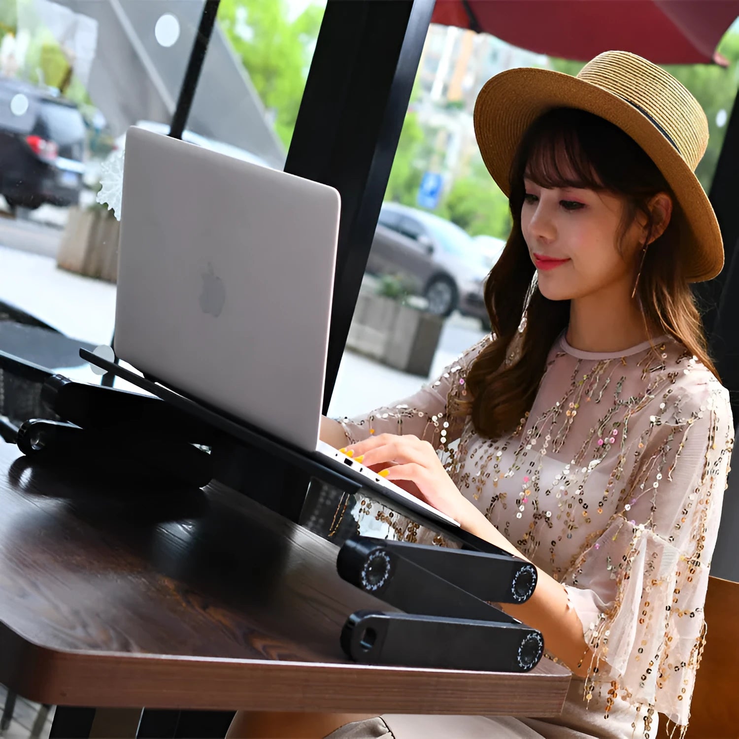 Red folding metal bed table with extended strap and cooling fan, holding a laptop.