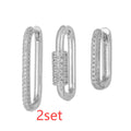 Three geometric square ear clips with inlaid zircon details in gold and white finishes on a grey background.