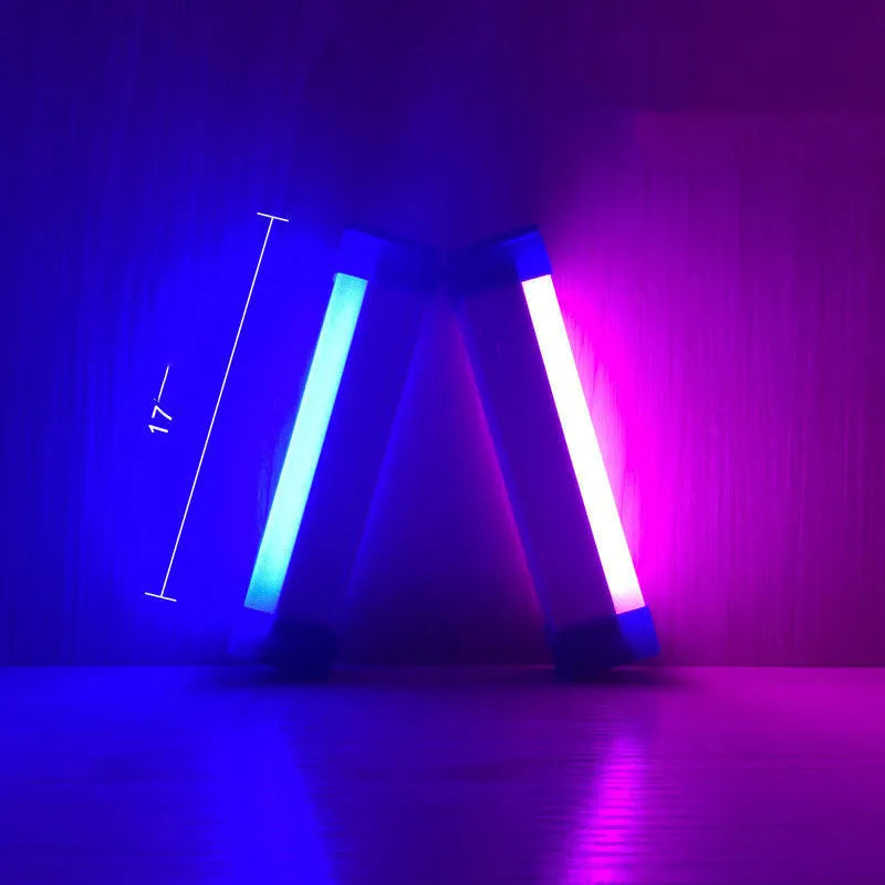 Blue and purple rechargeable LED tube light with USB cable on a dark background.